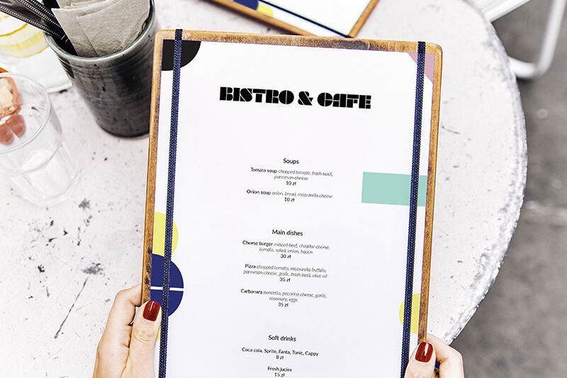 Mockup Featuring Hand Holding Restaurant Menu with a Table at Background