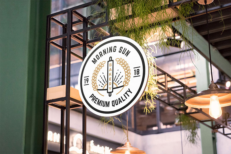 Circular Shop Sign Attached to Building Decorated with Plants and Lamps Mockup