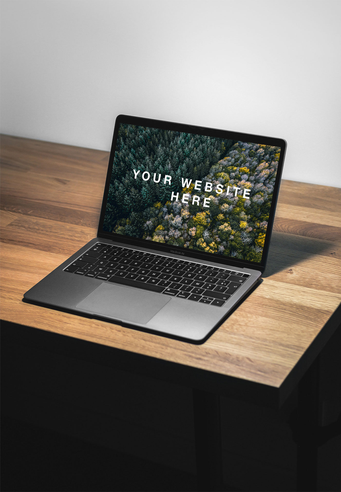 Mockup Featuring 3/4 View a MacBook Air Facing Light on a Desk